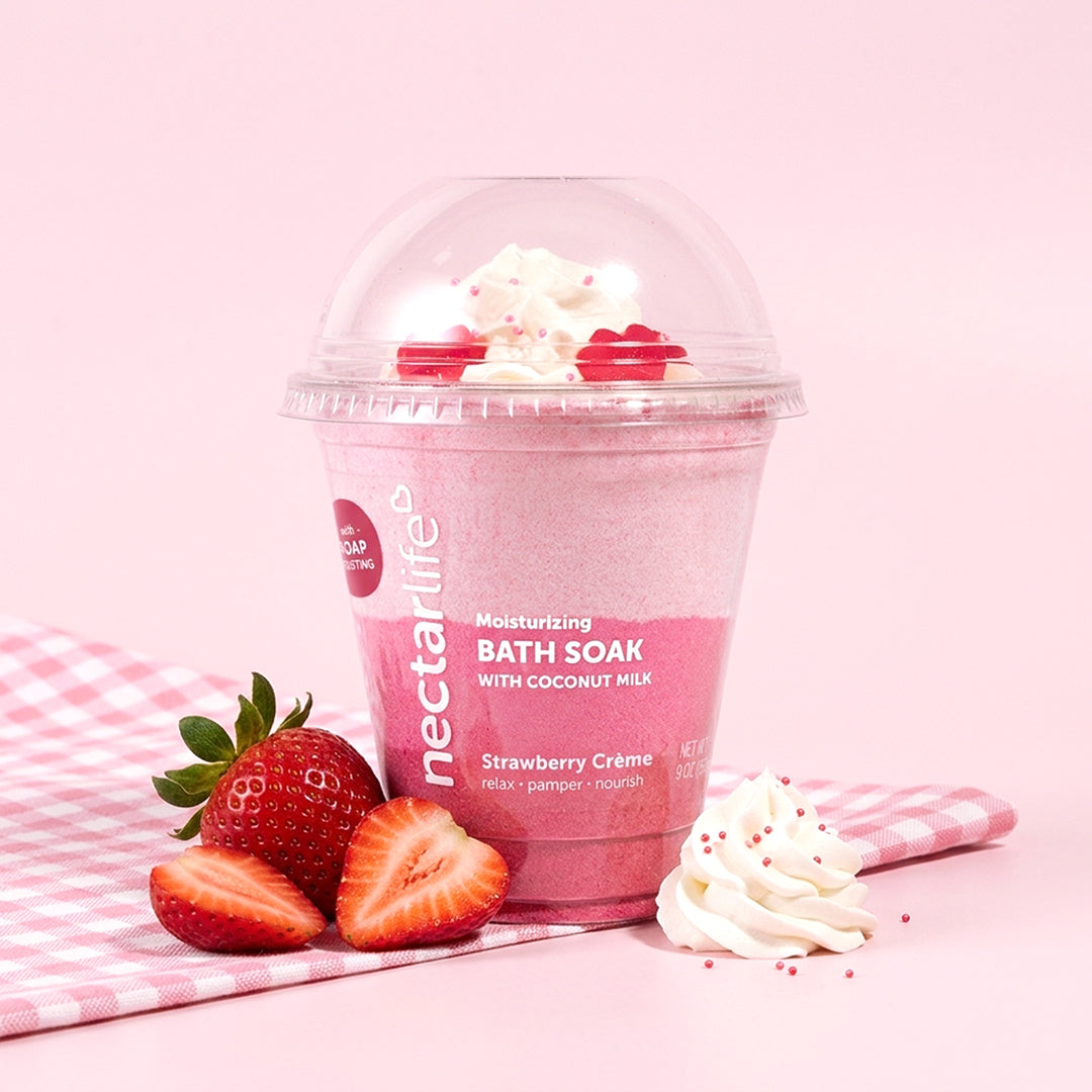 Strawberry Crème Milkshake Bath Soak by Nectar Life styled with fresh strawberries and whipped cream on a pink gingham background, 9oz