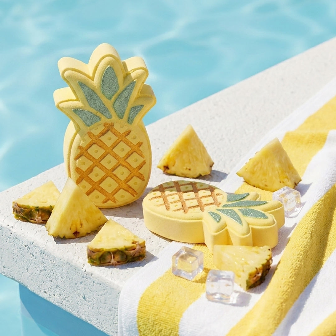 Nectar Life Tropical Pineapple Bath Bombs on a sunny pool ledge surrounded by fresh pineapple slices and ice cubes, with a yellow striped towel and blue water in the background