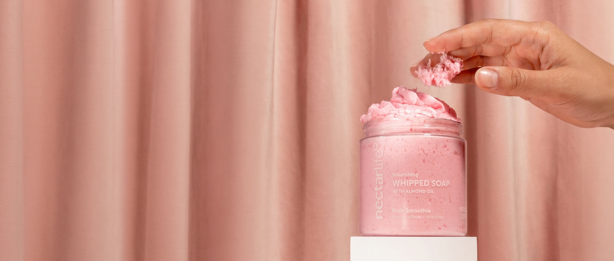 Swirls of pink, blue, purple, and white whipped soap beside a jar of Nectar Life Lavender Blossom Nourishing Whipped Soap and Shave Butter