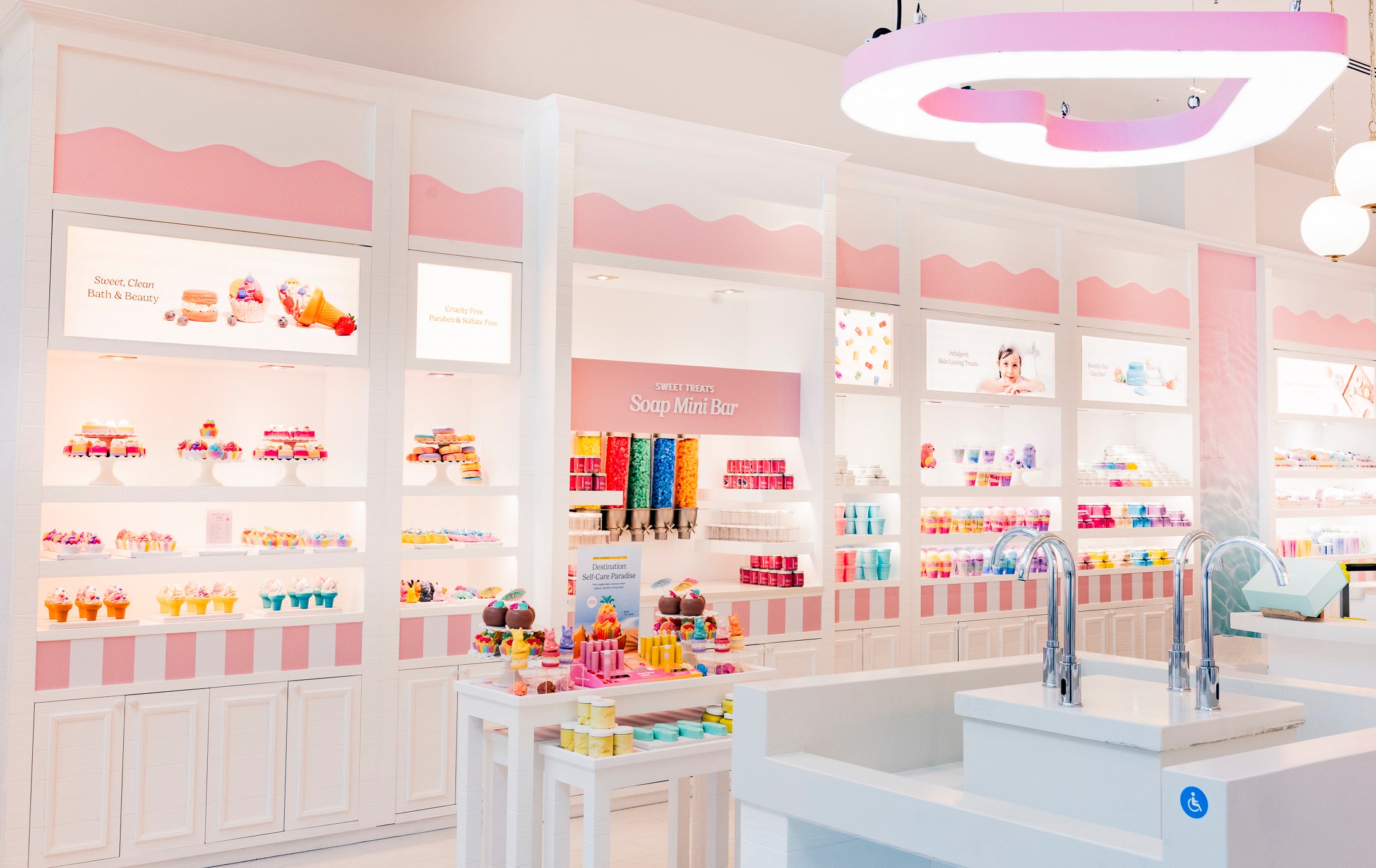 Inside a Nectar Life store: pink and white shelves of colorful bath treats and the Soap Mini Bar sink station