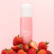 Strawberry Crème Nourishing Dry Body Oil by Nectar Life, pink spray bottle surrounded by fresh whole and sliced strawberries on a pink background, with rosehip oil and jojoba oil, 3.4 fl oz