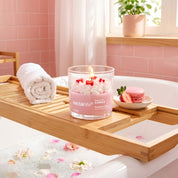 Nectar Life Strawberry Crème Candle burning on a wooden bath tray beside a bubble bath, clean-burning coconut wax, up to 50 hours burn time