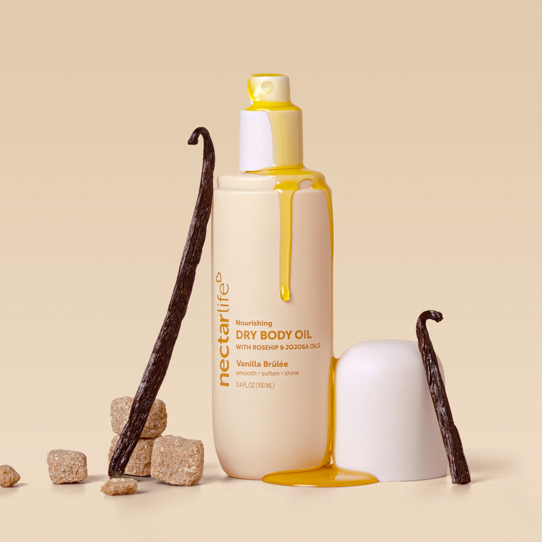 Nectar Life Vanilla Brûlée Dry Body Oil bottle with golden oil and vanilla bean props, glow-boosting dry body oil with olive squalane and rosehip, 3.4 fl oz