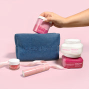 Hand placing Nectar Life Strawberry Crème products into a dark denim travel pouch, gift set with body butter and sugar scrub