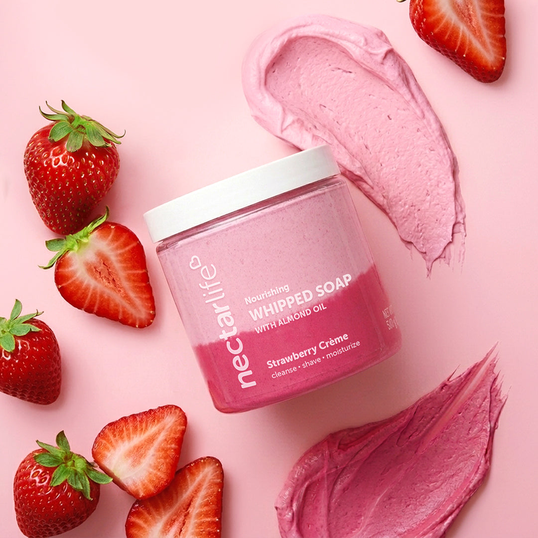Nectar Life Strawberry Crème Whipped Soap jar surrounded by fresh strawberries on a pink background, award-winning 3-in-1 formula, 5oz