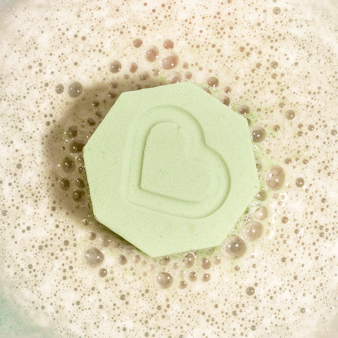 Nectar Life Essential Oil Benefit Bomb fizzing in warm water overhead view, releasing clarifying essential oils with niacinamide and fractionated coconut oil