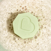 Nectar Life Essential Oil Benefit Bomb fizzing in warm water overhead view, releasing clarifying essential oils with niacinamide and fractionated coconut oil
