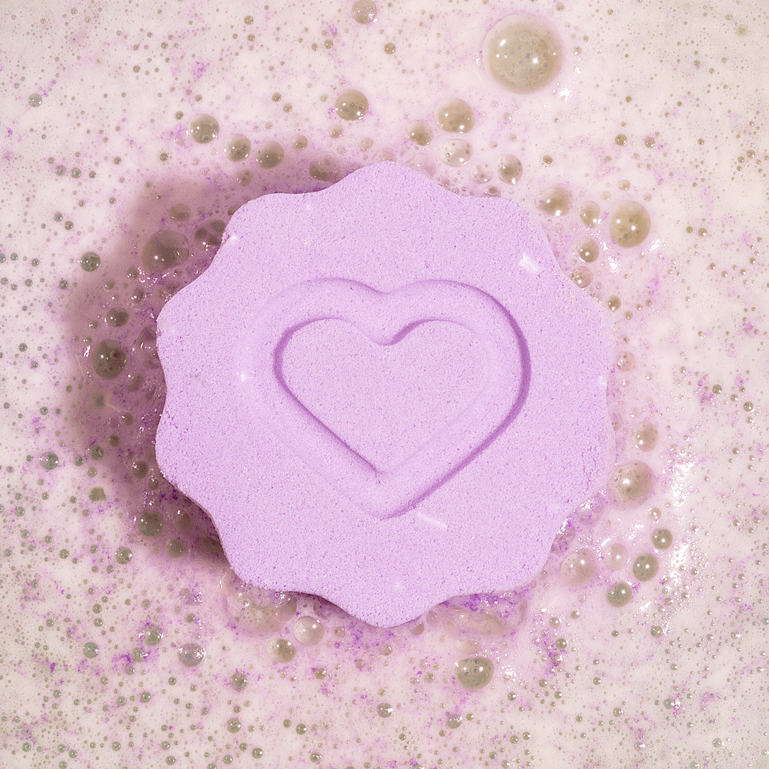 Nectar Life Soothe + Recover Magnesium Bath Bomb fizzing in warm water overhead view, releasing lavender and geranium essential oils with magnesium and Epsom salt
