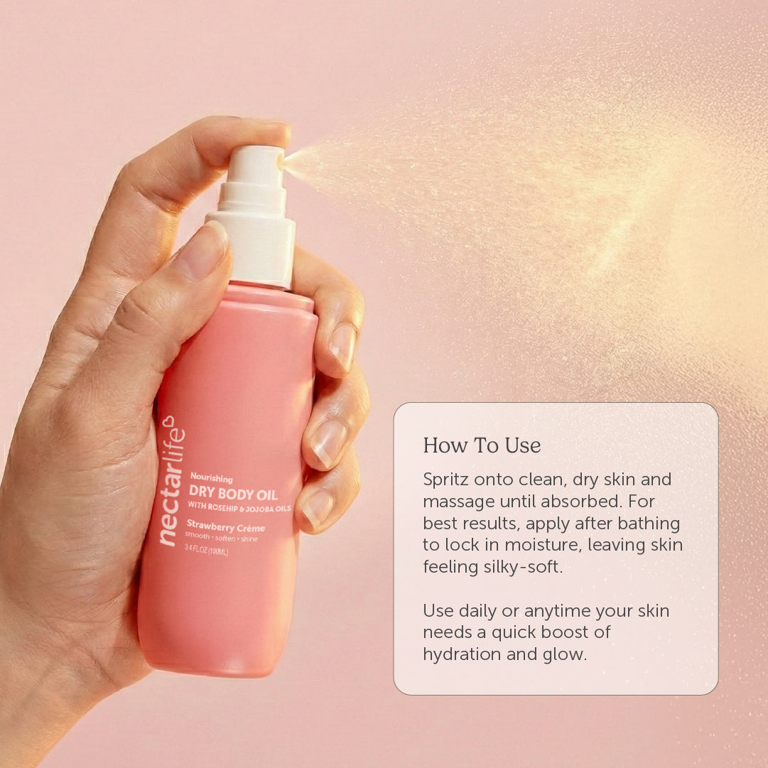 Hand spraying Nectar Life Strawberry Crème Dry Body Oil onto skin, fast-absorbing formula with rosehip oil and olive squalane, 3.4 fl oz