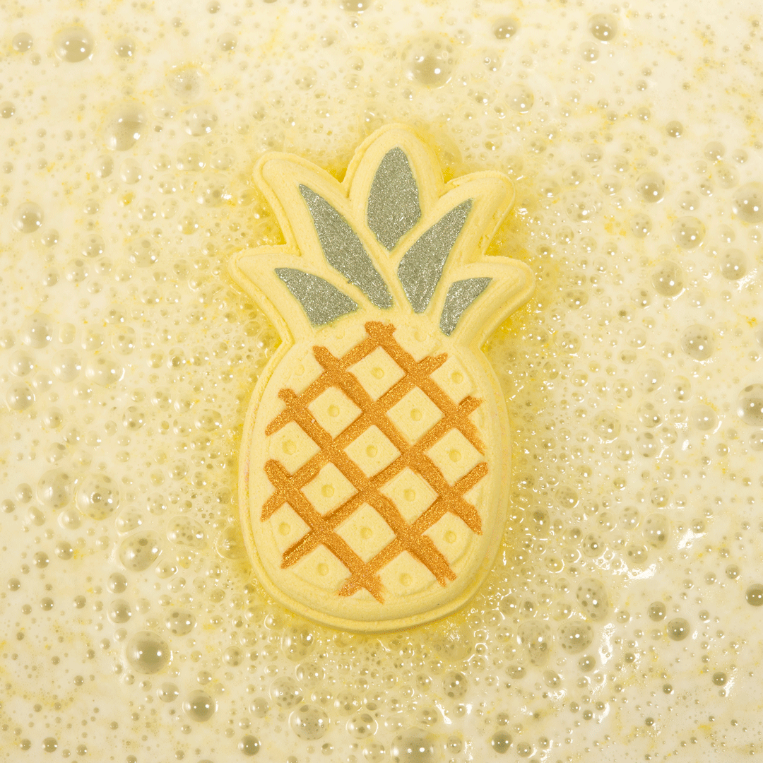 Nectar Life Tropical Pineapple Bath Bomb floating in golden fizzing bath water, pineapple-shaped bath bomb with glittery green crown dissolving in a bubbly soak