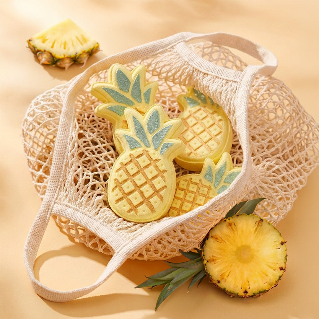 Nectar Life Tropical Pineapple Bath Bombs in a cream mesh tote bag surrounded by fresh pineapple pieces on a warm golden background