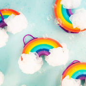 Multiple Nectar Life Large Rainbow Loofah Bath Sponges floating on turquoise water with soap bubbles, showing the rainbow sponge body and white mesh loofah clouds from above